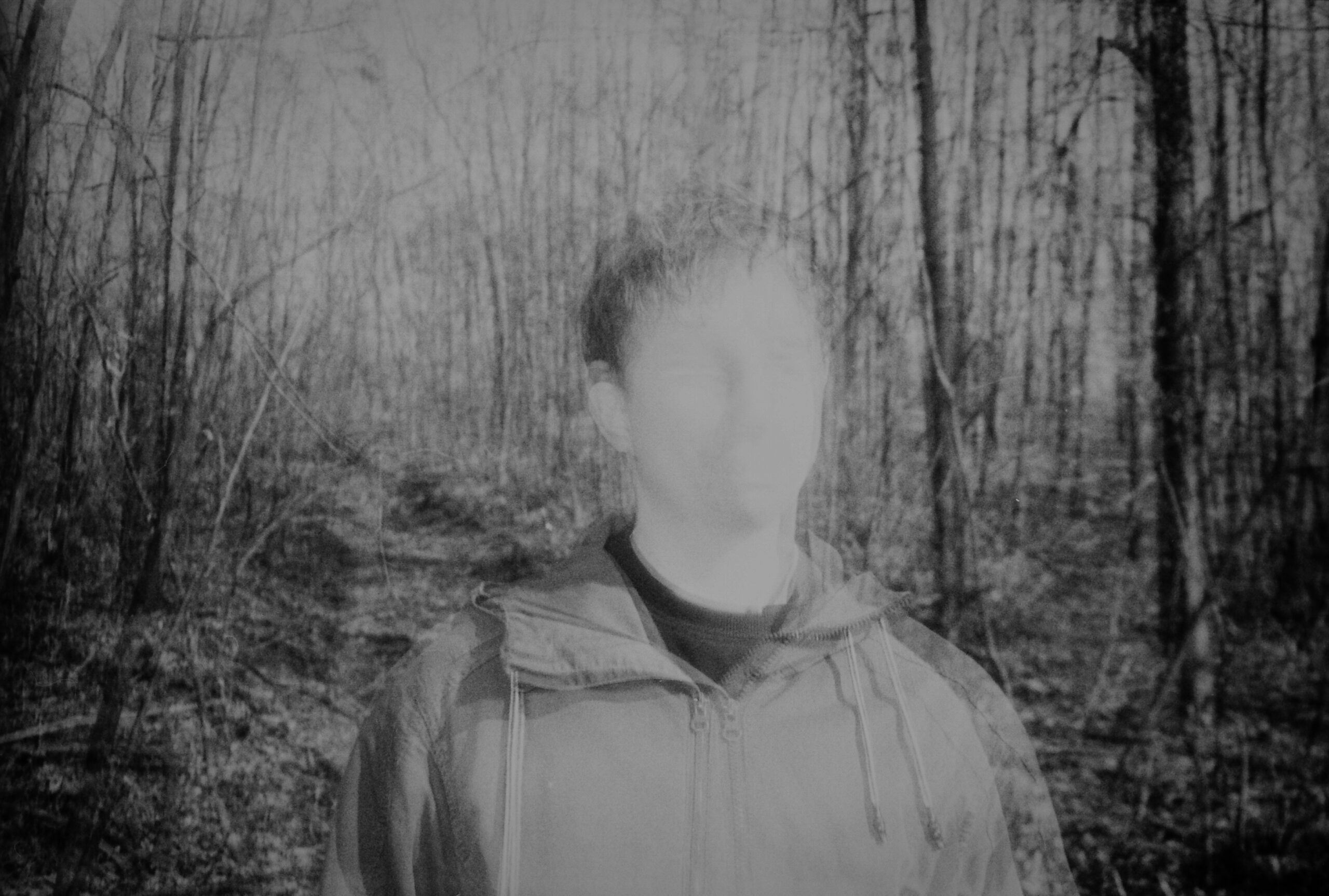 Black and white artistic portrait with a blurred face and textured dark background, representing the Cerny tesak persona.